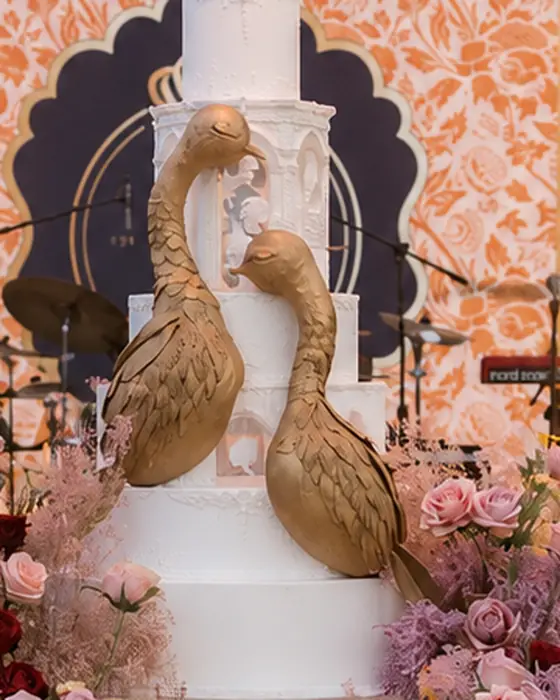 Gilded sugar peacocks on a white tiered cake