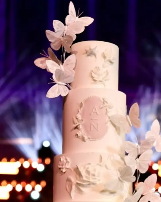 Close detail of sugar butterflies rising past the monogram plaque