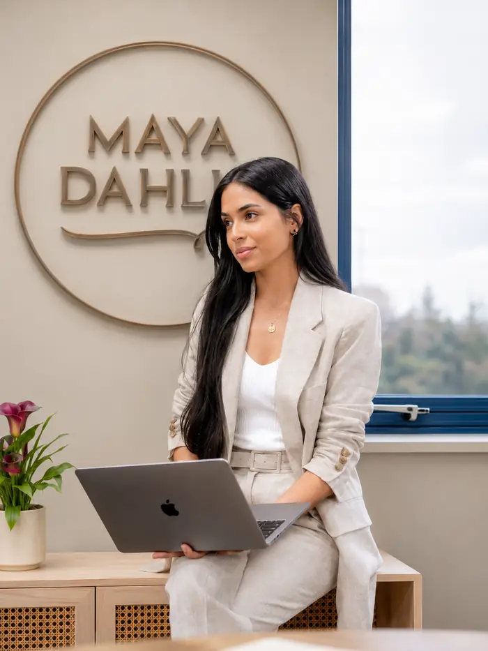 Krishma in the Maya Dahlia studio, beneath the brand's circular signage on the wall