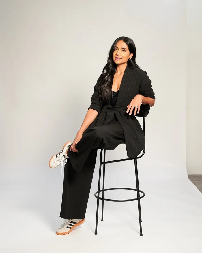 Krishma in a kitchen holding a mug, smiling towards the camera